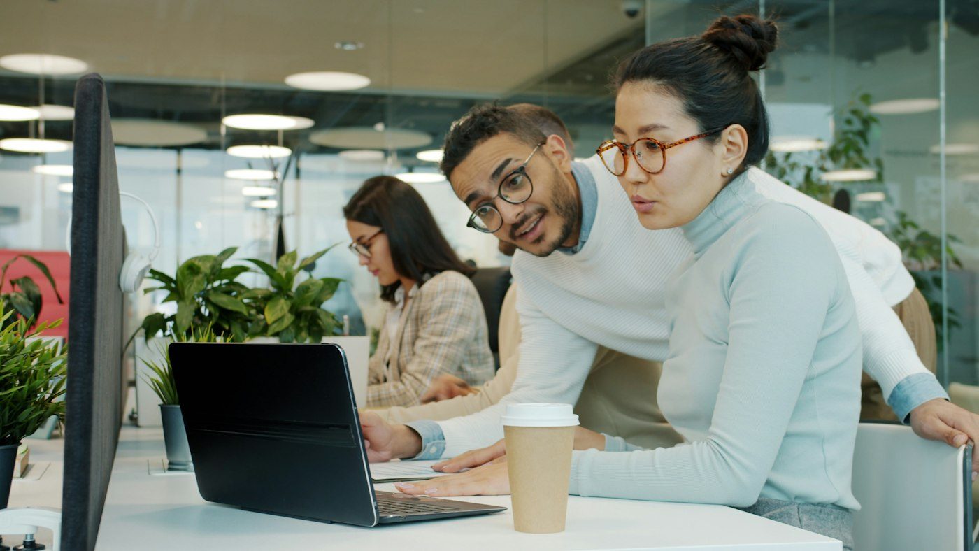 Colleagues collaborating at a laptop in a modern office